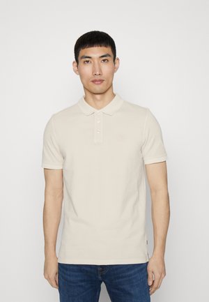 Polo beige in cotone con colletto classico, chiusura a tre bottoni e maniche corte. Dettaglio logo discreto sul petto.