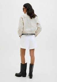 Juodi odiniai auliniai batai su blokuotu kulnu, derinami su balta mini sijonu ir dryžuota bežine striuke, turinčia elastingas rankoves ir prigludusį liemenį.