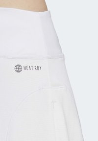 Fehér sportnadrág sima derékrésszel, texturált anyagból, a tetején a "HEAT.RDY" felirattal. Lélegző dizájn jellemzi.