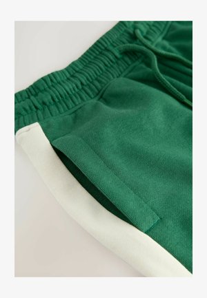Grüne Baumwollshorts mit einem elastischen Bund, versehen mit einem weißen Seitenpanel. Der Stoff ist weich mit einer glatten Textur.