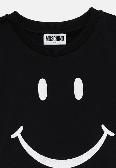 Juoda marškinėliai su apvaliu kaklu. Savybė - didelė balta siuvinėta šypsenėlė dizaino centre. Etiketėje užrašyta "Moschino Kid."