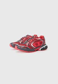 Red and black athletic shoes feature a mesh upper with textured accents, sturdy rubber soles, and reflective laces. Design includes bold detailing.
