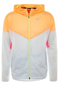Chaqueta de running de Nike, con un diseño de bloques de color naranja y blanco, material ligero, capucha ajustable y un logo reflectante.