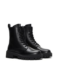 Bottes de combat en cuir noir avec une tige lisse, un laçage à l'avant, une fermeture éclair sur le côté et une semelle épaisse et crantée.