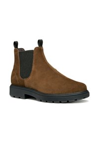 Botas Chelsea de ante marrón con paneles laterales elásticos negros y lengüetas para tirar. Cuentan con una suela de goma negra gruesa con un dibujo texturizado.