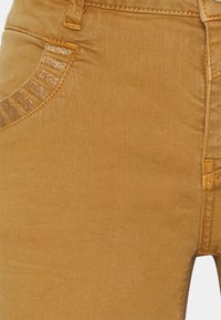 Žluté džínové kalhoty se slim fit, s texturovaným designem kapes, metalickými akcenty a kontrastním prošíváním.