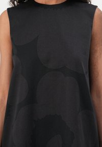 Black sleeveless dress featuring a texture with large, abstract floral patterns. Crafted from smooth fabric with a relaxed fit.