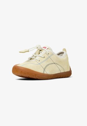 Chaussure en daim beige clair avec lacets blancs, bout rond et semelle en caoutchouc de couleur marron clair. Présente des détails de couture et un petit logo sur le talon.
