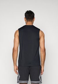 Μαύρο αμάνικο αθλητικό τοπ με στρογγυλή λαιμόκοψη, κατασκευασμένο από λείο ύφασμα, σε συνδυασμό με μαύρο σόρτς με υφή και λευκές λεπτομέρειες.