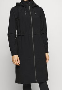 Svart, långärmad jacka med huva, framdragkedja, elastiska mudd och dragsko i midjan. Tillverkad av mjukt, lätt material.