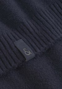 Marineblaue Wollmütze mit einem gerippten Design und einem flachen Etikett mit einem Logo, das die weiche Textur und den enganliegenden Sitz betont.