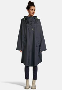 Poncho résistant à l'eau de couleur gris foncé avec capuche, boutons-pression et deux poches latérales. Présente des accents vert vif et une coupe ample et droite.