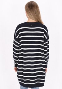 Marineblauw en witte gestreepte lange trui met een ontspannen pasvorm, geribde manchetten en een subtiel logodetail bij de achterkant van de halslijn. Zachte knittextuur.