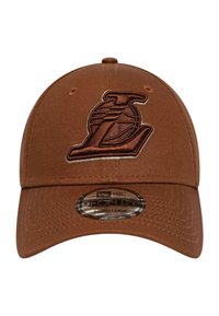 Braune verstellbare Kappe aus einem strukturierten Stoff, mit einem gestickten Logo auf der Vorderseite und einem runden Aufkleber auf dem Schirm.