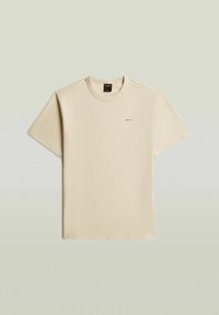 T-shirt beige à manches courtes avec col rond, texture gaufrée subtile et petit logo "G-STAR" sur la poitrine gauche.