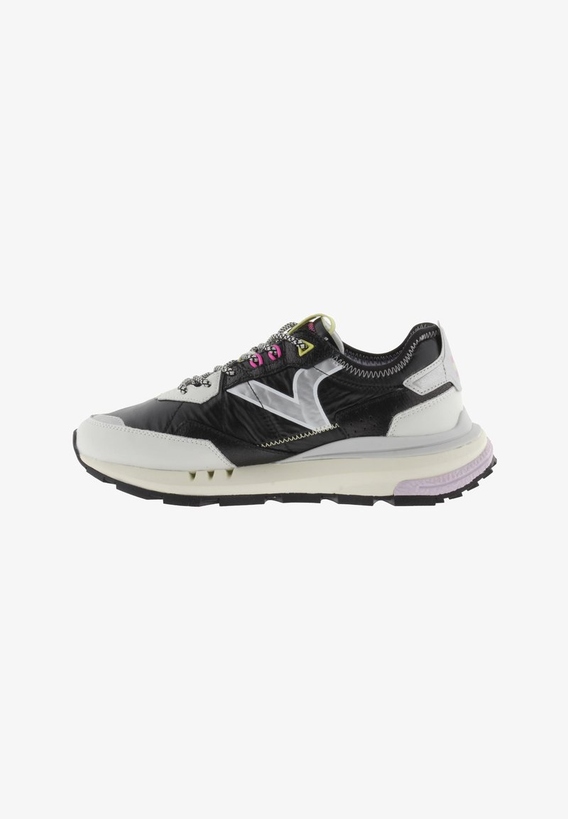 Sneaker bianco e nero con una tomaia nera testurizzata, dettagli riflettenti, occhielli dei lacci giallo fluorescente e una suola imbottita di colore viola chiaro.