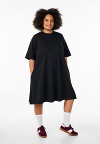 Černé, oversized tričko šaty s krátkými rukávy a bočními kapsami. Vyrobeno z měkké látky, s kulatým výstřihem a volným střihem.
