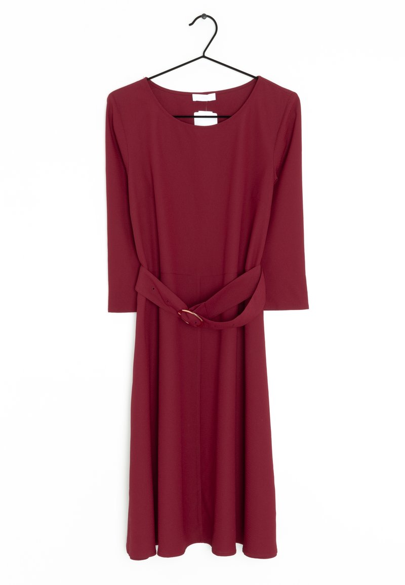 Burgunderrotes langärmeliges Kleid mit rundem Ausschnitt und einem gebundenen Stoffgürtel, der an einem schwarzen Kleiderbügel vor einem weißen Hintergrund hängt.