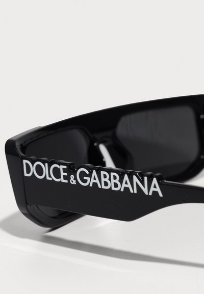 Melni saulesbrilles ar izteiksmīgu biezu apdari. Izceltas baltas "DOLCE & GABBANA" markas uzraksts uz kājas. Tumši lēcas un spīdīga apdare.