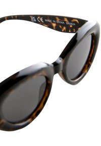 Tortoiseshell sunglasses with black frames, rounded lenses, and thick arms. Textured pattern on the inner frame. CE and UKCA markings visible.