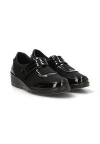 Scarpe nere con una finitura in vernice elegante, strap in velcro e lati perforati; suole a zeppa offrono maggiore altezza e comfort.