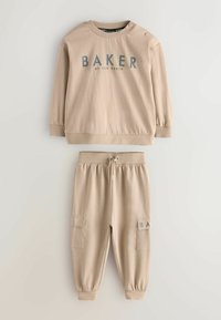 Béžová mikina s nápisem "BAKER" a detaily s knoflíky; ladící béžové tepláky s elastickým pasem, kapsami a logem na nášivce. Měkká látka.