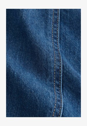 Tmavomodrá denímová tkanina s hladkou textúrou a viditeľným šitím. Obsahuje jemný lesk a diskrétny keper.