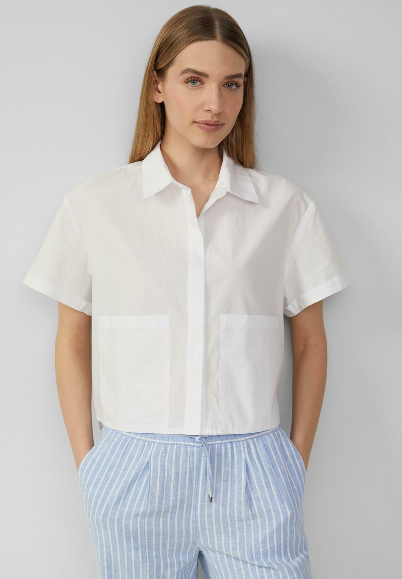 Witte kortlijdens knoopshirt met kraag, voorzien van twee borstzakken en een gladde, lichte stof.