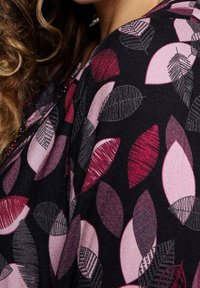 Tissu noir à motif de feuilles en nuances de rose et de bordeaux. Les feuilles varient en taille et en design, certaines présentant des détails texturés.