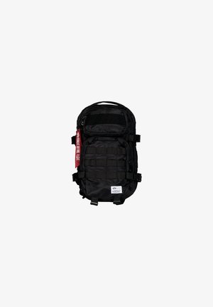 Black backpack made of nylon with multiple compartments, adjustable straps, webbing for attachments, and a red tag accent.