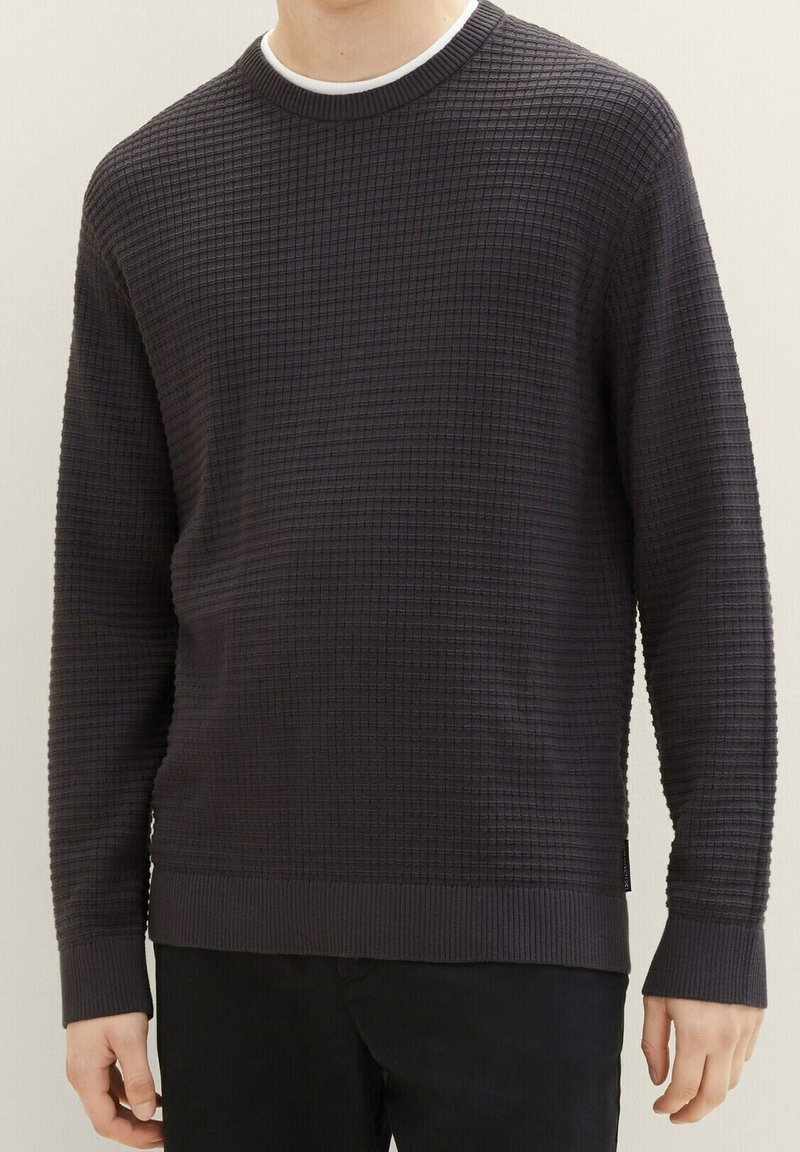 Maglione grigio con texture e motivo a quadri, con scollo e polsini a costine. Tessuto morbido e maniche lunghe, progettato per un look casual.