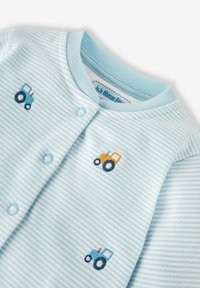 Helles blau gestreiftes Baby-Overall mit Druckknopfverschlüssen, versehen mit gestickten Traktor-Designs in Blau und Orange. Aus weichem Baumwollmaterial.