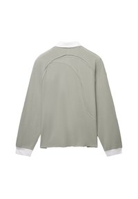 Camicia a maniche lunghe in tessuto verde chiaro con colletto bianco e un design cucito unico sul retro, caratterizzata da una vestibilità rilassata e una texture morbida.