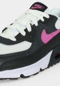 Ανδρικό παπούτσι Nike Air Max ασπρόμαυρο με ροζ λογότυπο Swoosh, λευκά κορδόνια και ορατό αερόσακο στη σόλα.