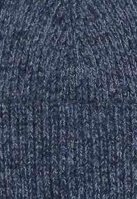 Kék kötött sapka struktúrált mintával. Bordás szegéllyel és puha, meleg felülettel rendelkezik, amely alkalmas hideg időjárásra.