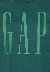Camiseta de algodón verde con grandes letras en color verde claro "GAP" en una fuente moderna. Suave al tacto y con cuello redondo.