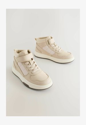 Tenisi bej tip ghete, cu un superior din piele netedă, șireturi elastice, o curea cu arici și o talpă din cauciuc texturată.