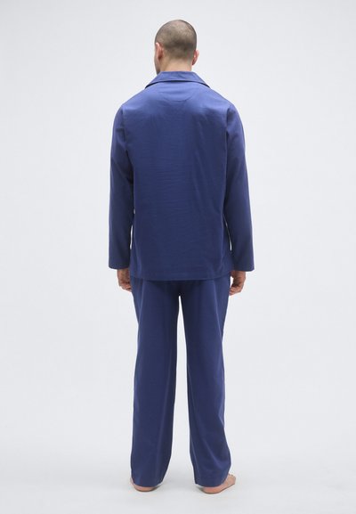 Σετ άνετης ένδυσης σε ναυτικό μπλε, που περιλαμβάνει πουκάμισο με μακριά μανίκια και γιακά και ταιριαστό παντελόνι, κατασκευασμένο από λείο ύφασμα με άνετη εφαρμογή.