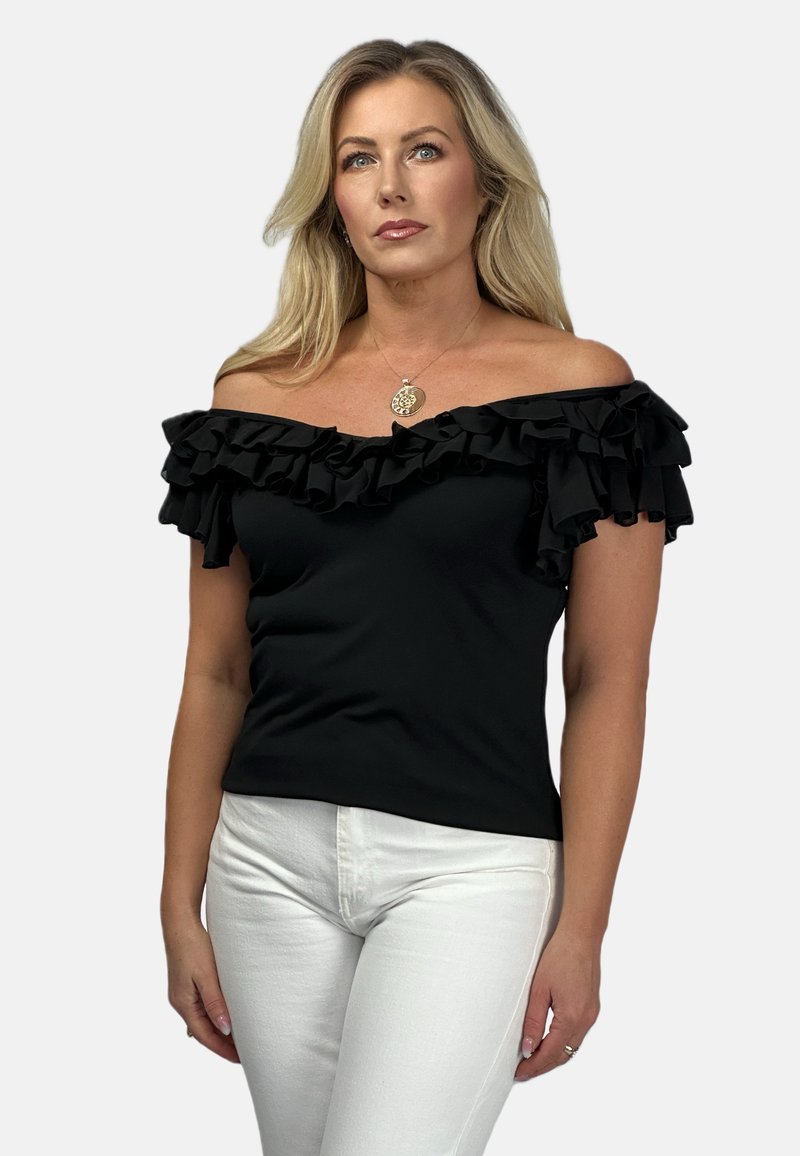 Czarny top bez ramiączek z falbanami, gładką strukturą i dopasowanym fasonem, w zestawieniu z białymi obcisłymi dżinsami.