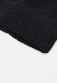 Black knit fabric with a ribbed texture. The edge is neatly finished, showcasing soft, dense fibers and a warm appearance.
