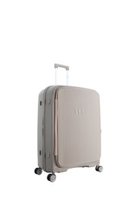 Hard-shell suitcase in light beige with vertical ribbed texture, retractable handle, and four black spinner wheels. Brand logo on front.