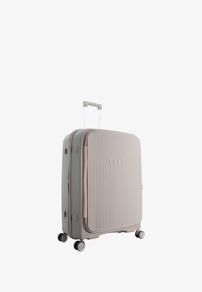 Hard-shell suitcase in light beige with vertical ribbed texture, retractable handle, and four black spinner wheels. Brand logo on front.