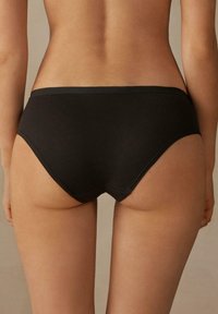 Zwarte katoenen slipjes met een gladde textuur, een middelhoog ontwerp en een naadloze tailleband. De snit is ontworpen voor een comfortabele pasvorm.