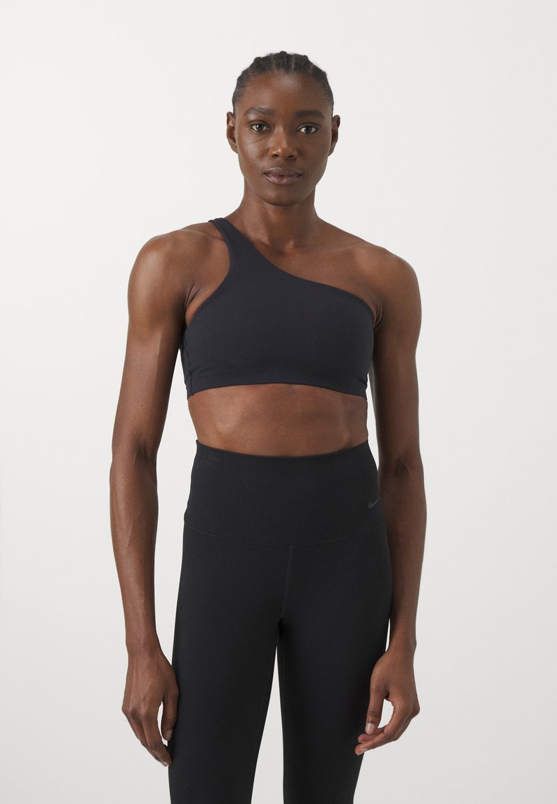 Bra sportivo nero a spalla unica realizzato in tessuto morbido ed elastico. Abbinato a leggings neri a vita alta con texture a righe.