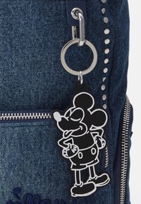 Plecak dżinsowy z srebrną kieszonką na zamek, okrągłym breloczkiem oraz czarnym gumowym urokiem z Myszka Mickey z białymi akcentami.