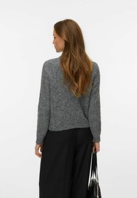 Grijs gestructureerd trui met lange mouwen, een ontspannen pasvorm en een afgeronde zoom, gecombineerd met zwarte wijde broekspijpen en een zwarte tas.