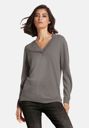 Grijze v-hals trui met lange mouwen, ribgebreide boorden en onderrand, gladde textuur en een licht relaxte pasvorm. Gekocht in combinatie met donkere jeans.
