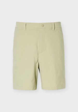 Shorts beiges mi-longs avec passants pour ceinture, fermeture à bouton sur le devant, et un design en tissu lisse et épuré, sur un fond uni.