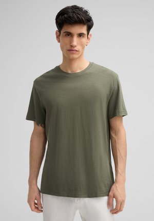 T-shirt verde oliva in cotone morbido e leggero. Collo rotondo classico, maniche corte, vestibilità rilassata. Design minimalista, senza motivi o accenti visibili.