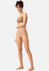 Bralette marrone leggero con spalline regolabili e slip a vita alta color carne. Entrambi hanno una texture liscia e un design senza cuciture.